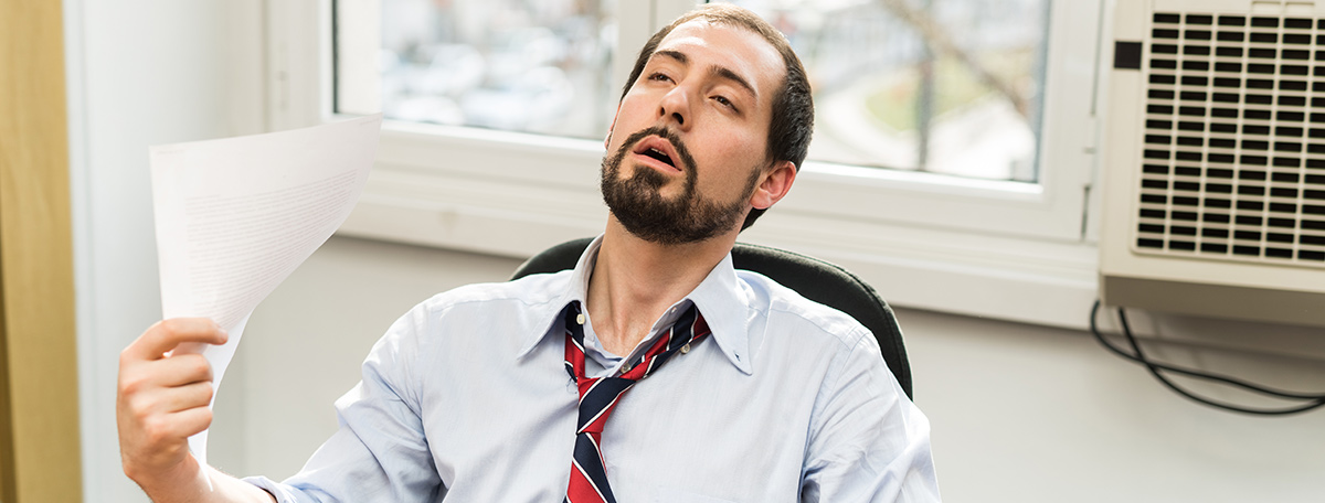 man fanning himself broken air conditioner in office