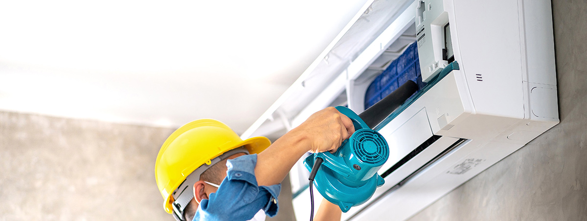 maintenance man doing air conditioner maintenance on wall AC unit