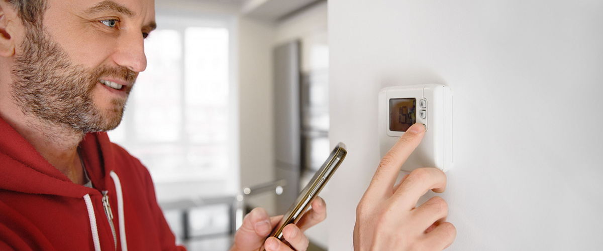 man looking his smartphone how temperature heater is regulated 