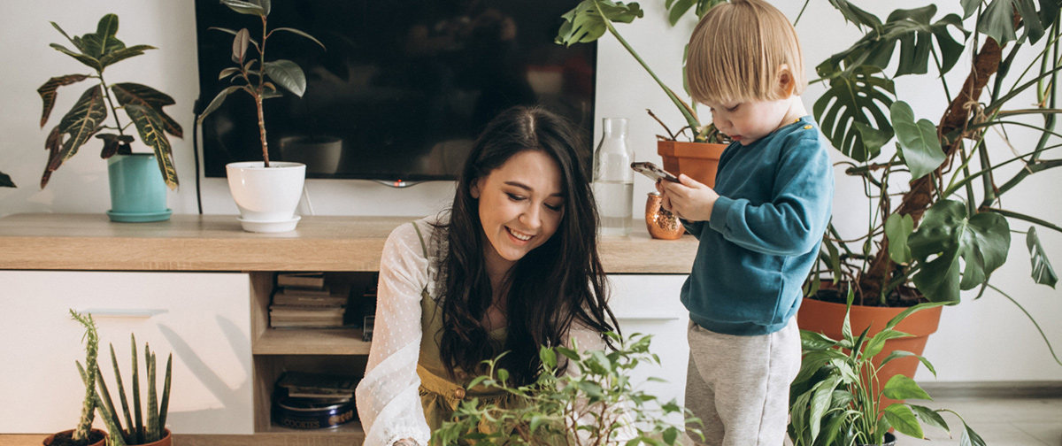 mother with little son cultivating houseplants