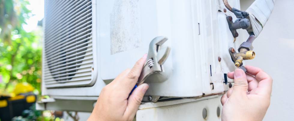 man repairing air conditioner outside home