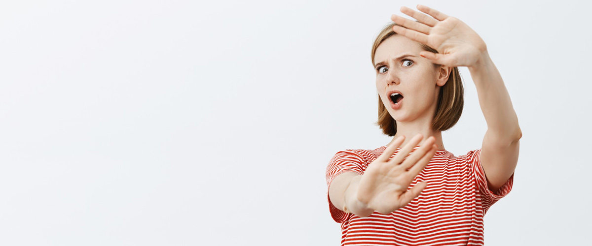 shocked freak out young woman raising hands defensive protecting herself 