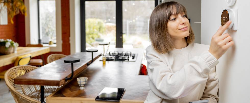 woman controlling home temperature with electronic thermostat