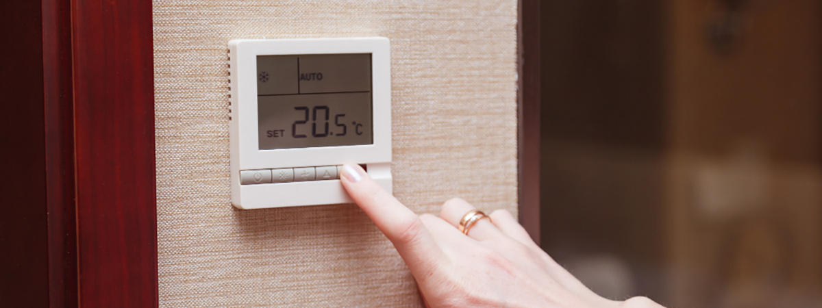 woman switching digital thermostat