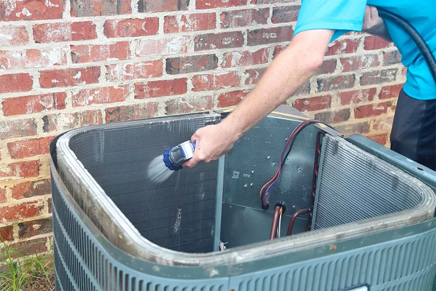 AC repair man cleaning ac coils