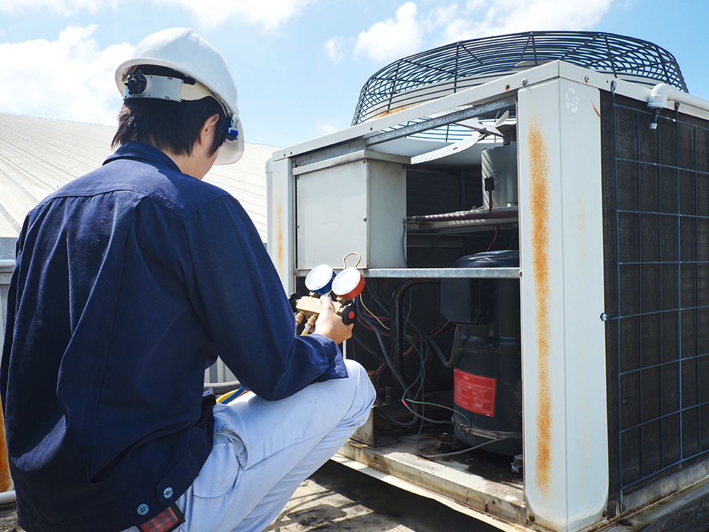 central air conditioner professional tech repairing unit on roof top